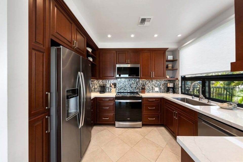 Modern kitchen with rich wood cabinetry, granite countertops, stainless steel appliances, and ample prep space, ideal for cooking meals at home.