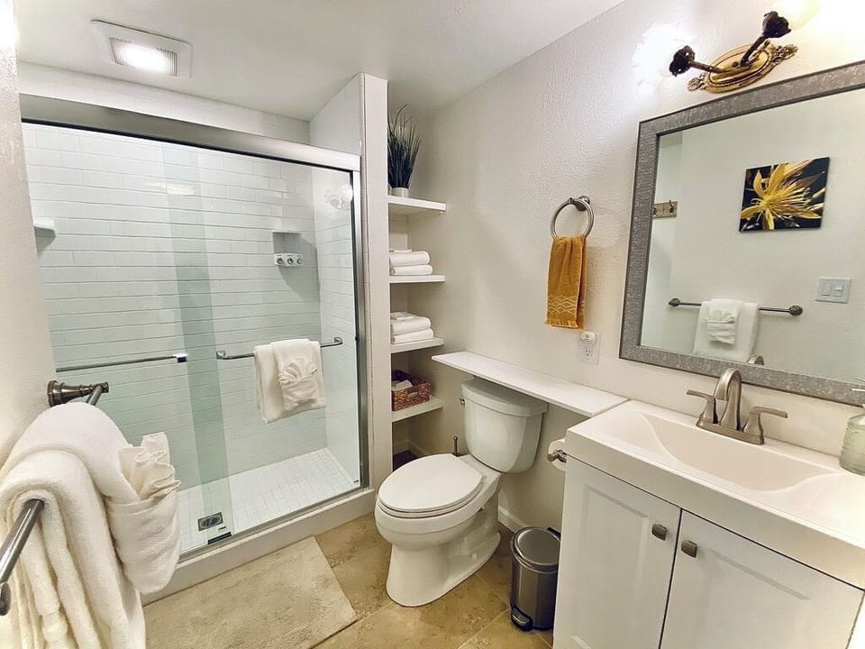 Clean fully stocked tile bathroom with hairdryer, shampoo, conditioner, and soap