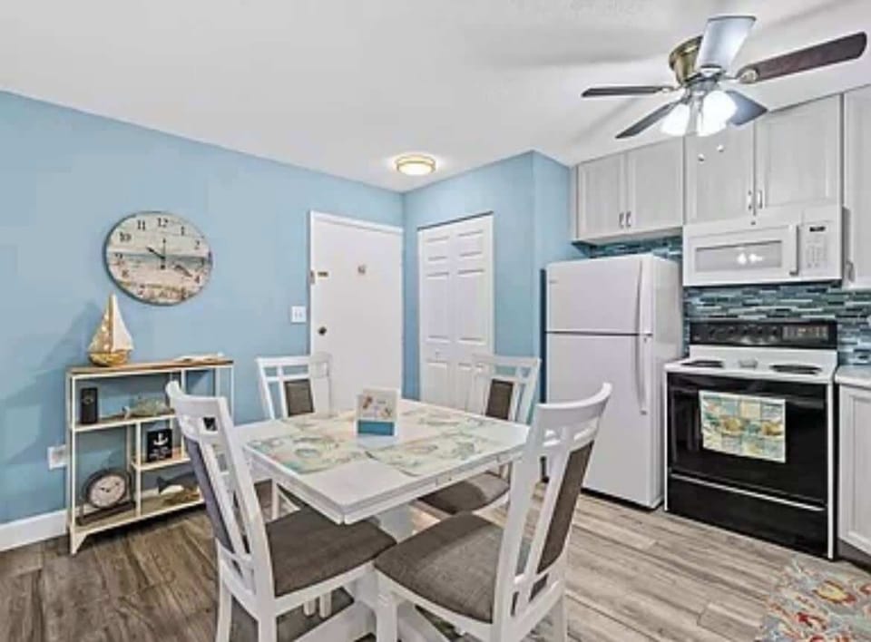 Cozy dining area with a coastal-themed kitchen featuring white appliances and blue walls.