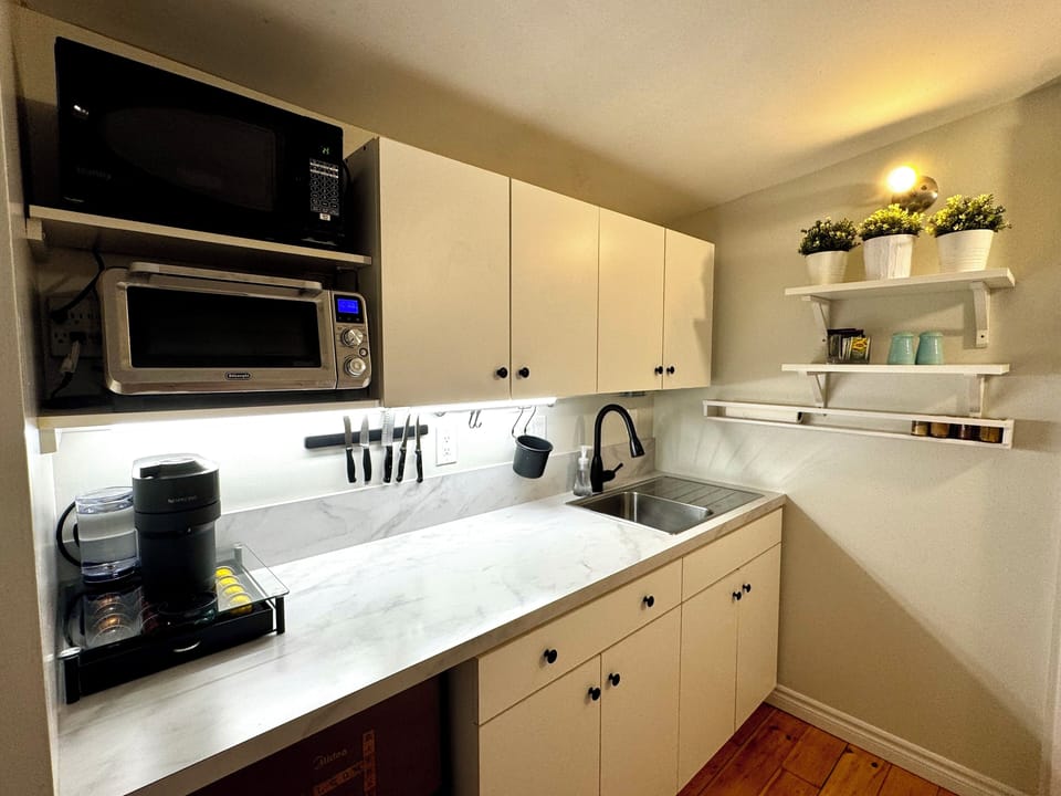 Fridge, cooktop, microwave, toaster, Nespresso, blender, utensils, dining area.