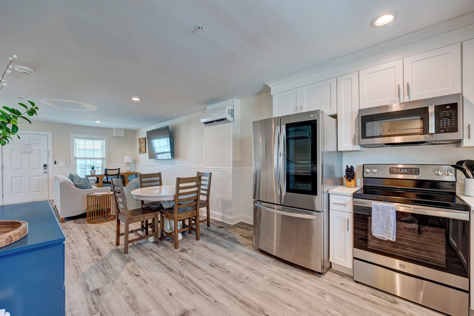 Your spacious open-concept kitchen flows seamlessly into the dining area, featuring stainless steel appliances and crisp white cabinetry perfect for preparing meals.