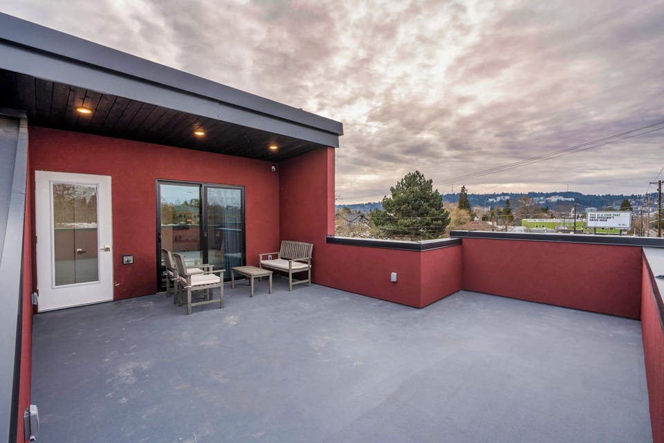 Rooftop terrace with two chairs beside a glass door.