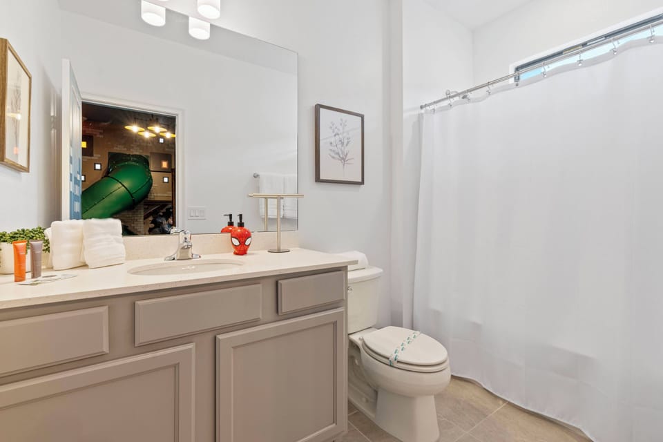 Enjoy a bright, functional bathroom featuring a sleek countertop, soft gray cabinetry, and ample space for your essentials. The clean white shower curtain and modern lighting create a refreshing atmosphere to start your day.