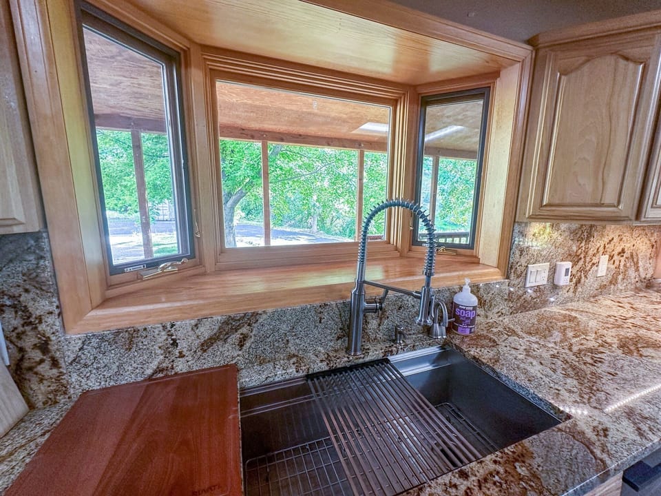 Nice farmhouse sink with peaceful views out the bay window