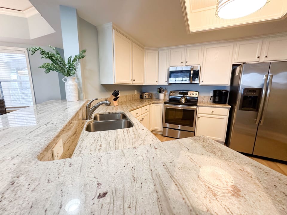 The kitchen features expansive granite countertops with a deep breakfast bar, perfect for casual dining and entertaining.