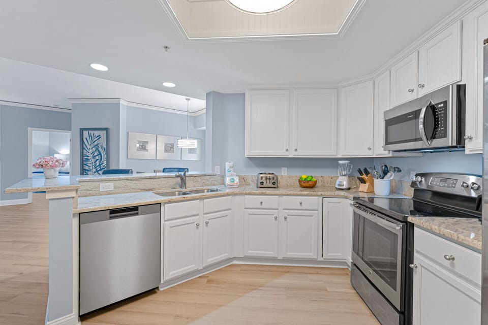 Crisp white cabinetry, stainless steel appliances, and a double-basin sink create a clean, functional workspace.