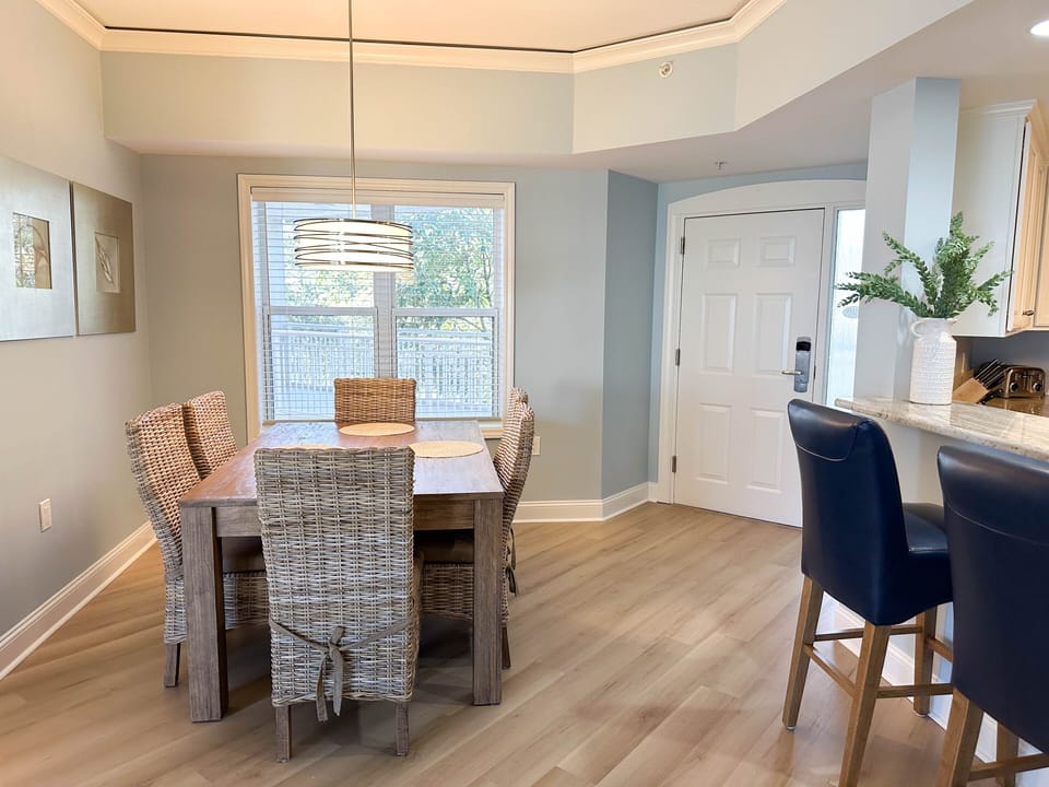 The dining area offers a comfortable space for shared meals, featuring a well-sized table with seating for six beneath a modern pendant light.