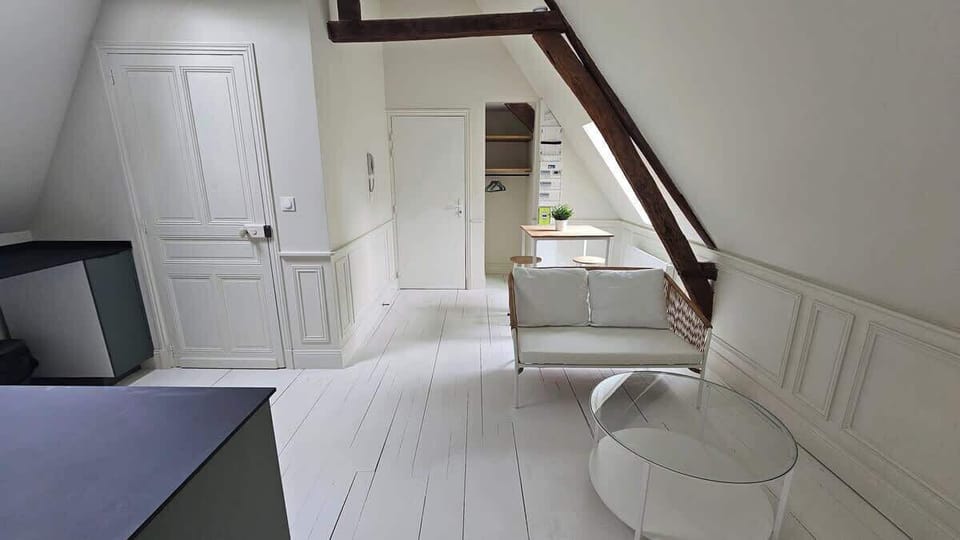 Salon avec canapé et coin repas pour deux personnes, ouvert sur la cuisine.