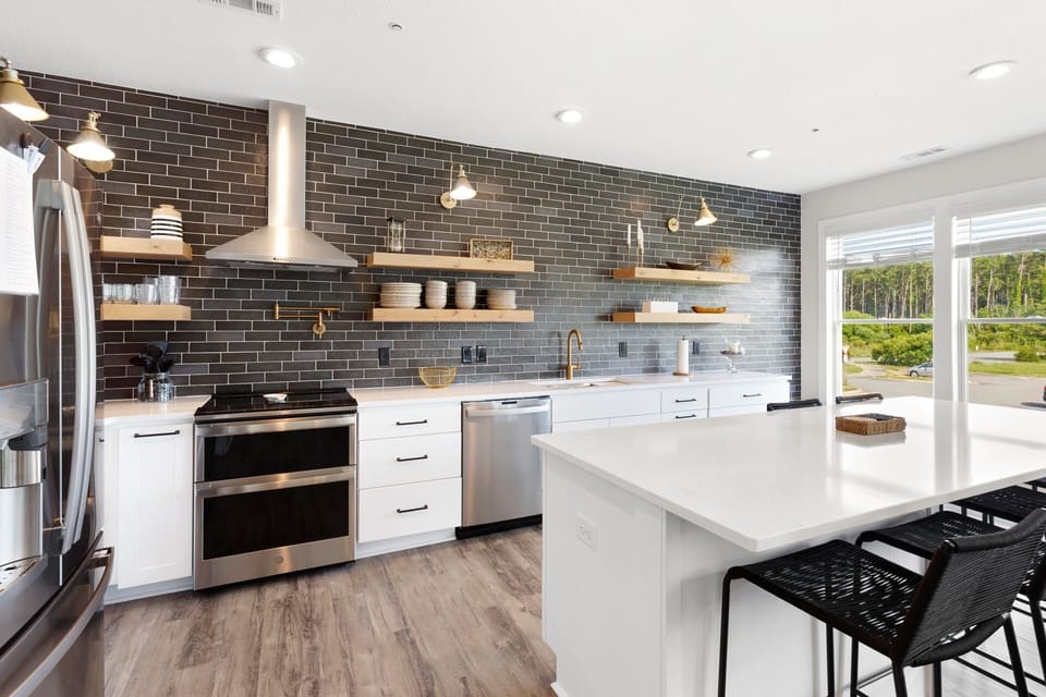 Cook in the Kitchen with modern appliances, a fully tiled wall, brickwork pattern, stainless steel appliances, and quartz countertops.