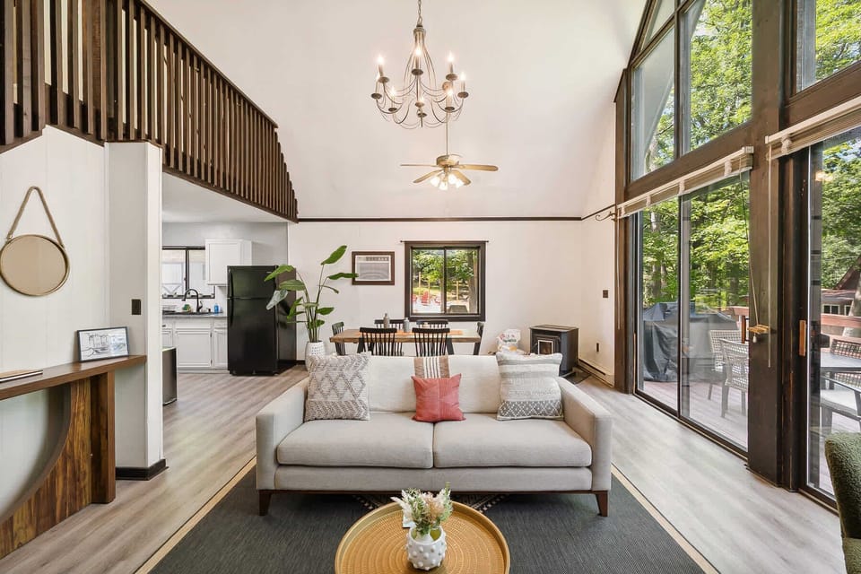 Open living area with vaulted ceilings and large windows overlooking the deck and forest.