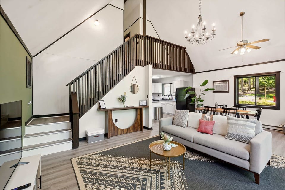Open living area with vaulted ceilings and a modern dining space overlooking the wooded outdoors.