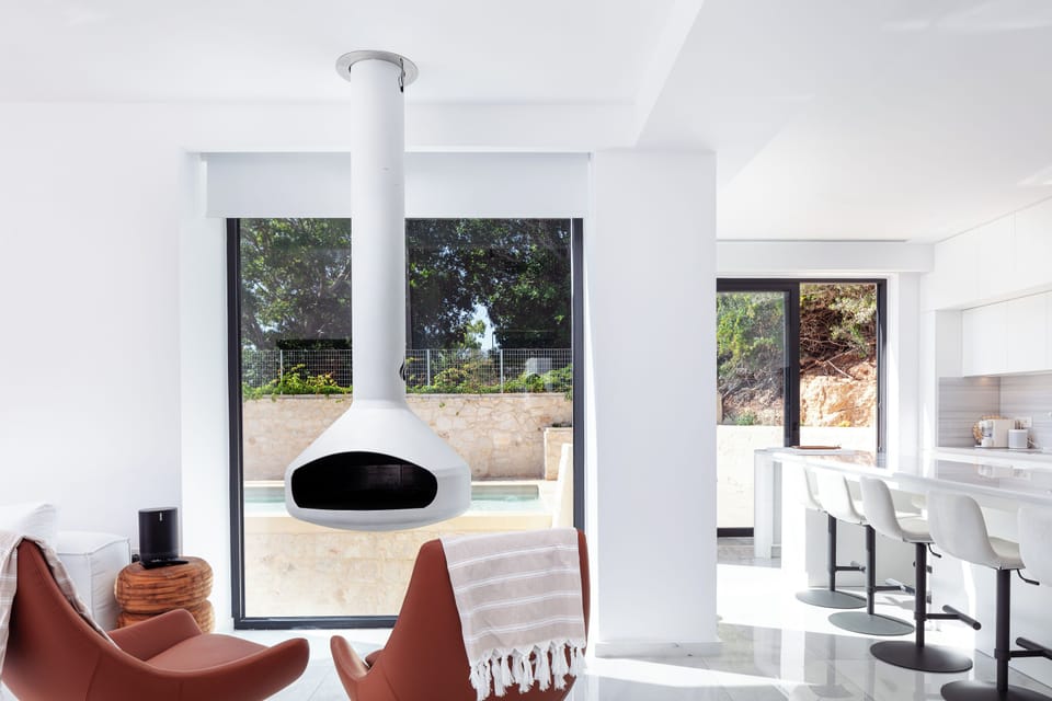 The main living room features a lush sofa, comfy armchairs, a 65” TV, and a cozy fireplace for chilly days.