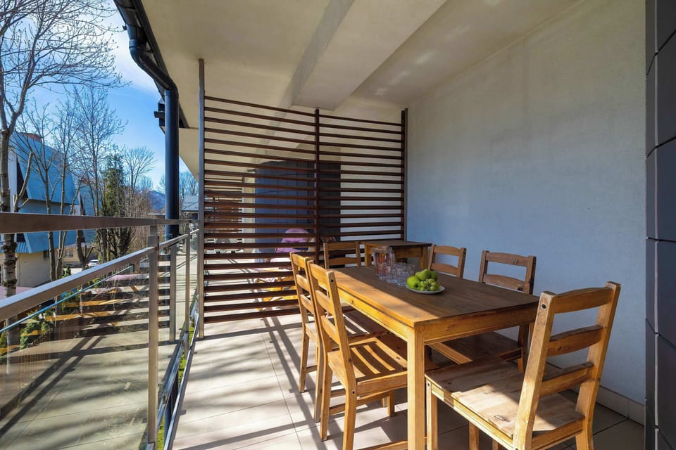 Cozy balcony area with wooden dining furniture and privacy panels.