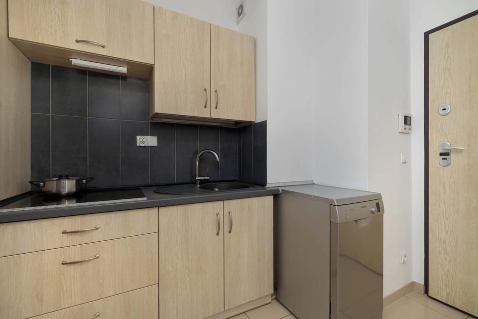 Well-equipped kitchen with light wooden cabinets and a black countertop.