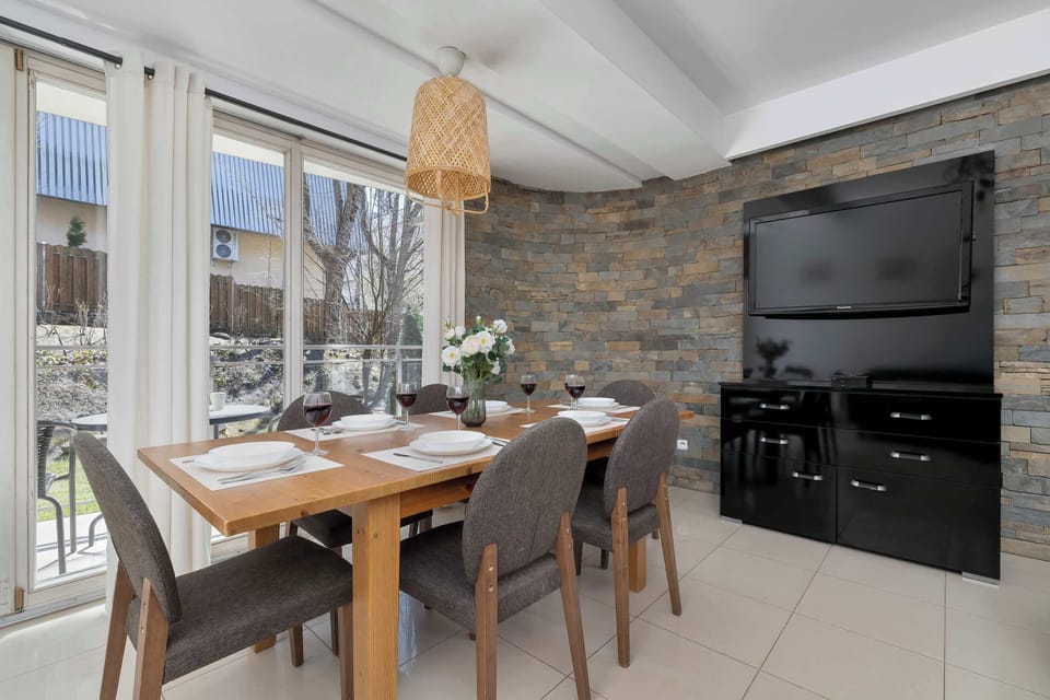 Open and bright living area with a green sectional sofa and dining table.