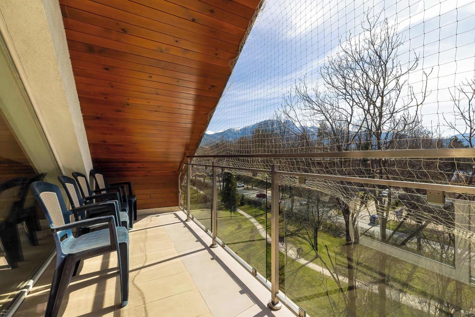 Outdoor space with table and chairs overlooking greenery and hills.
