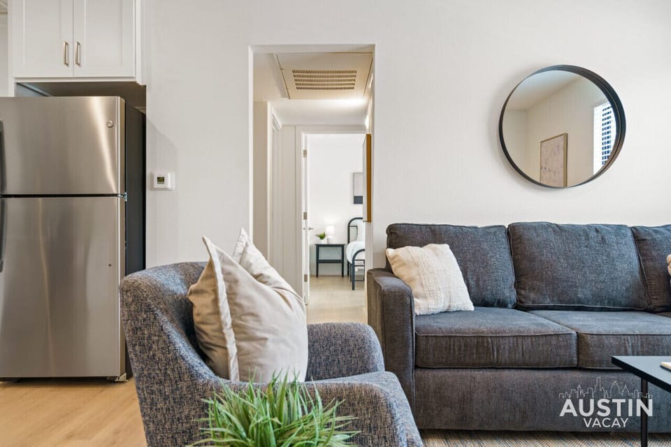 Bright living room with comfortable seating, smart tv, and queen sleeper with bedding