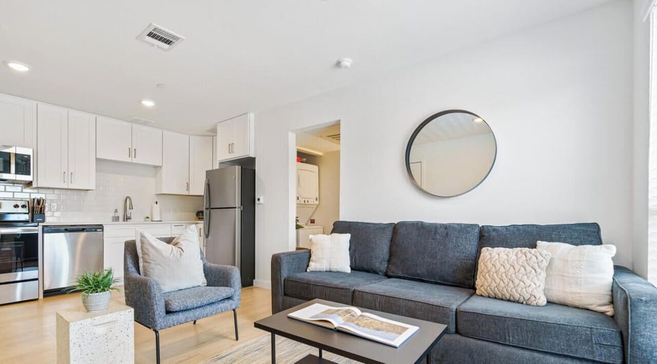 Bright living room with comfortable seating, smart tv, and queen sleeper with bedding