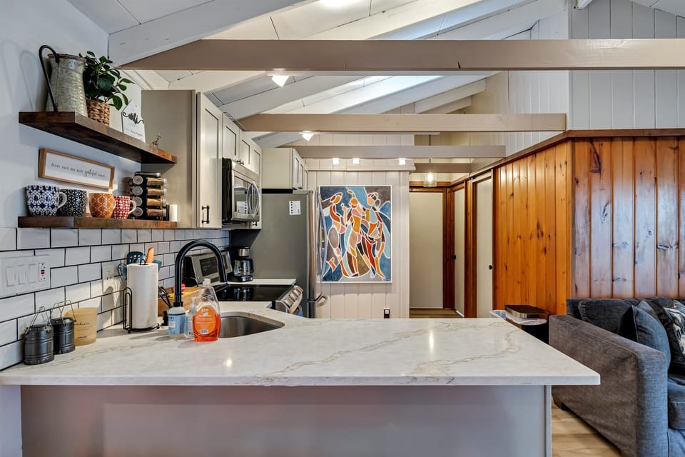 Modern kitchen with sleek quartz countertops, stainless steel appliances, and a breakfast counter, offering a stylish and functional space for cooking and dining | Serhii Vacation Rentals