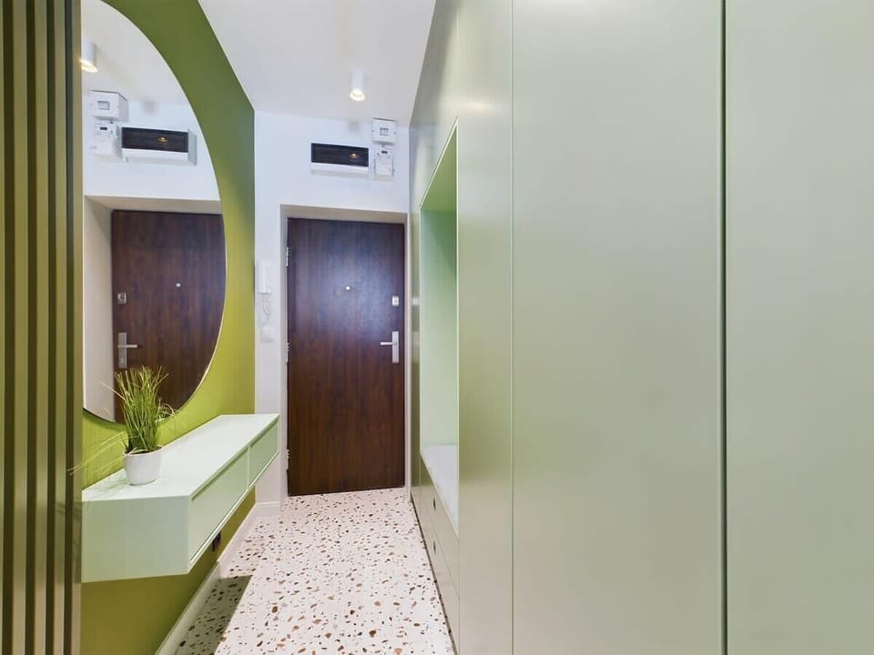 Hallway with green cabinetry and arched doorway mirror – fresh and creative interior detail.