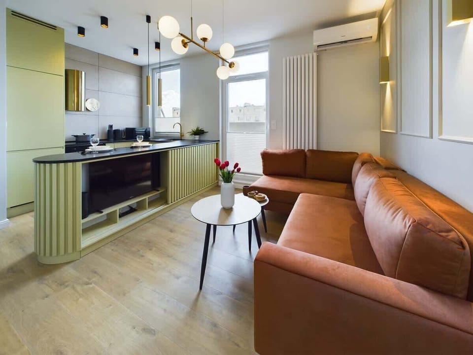 Living area with elegant round table, modern chandelier, and caramel leather sofa – cozy and stylish atmosphere.