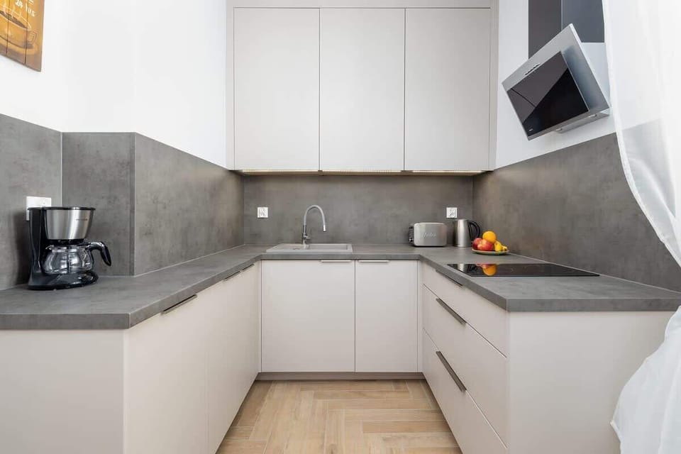 A compact kitchenette with modern cabinetry and appliances for preparing meals with ease. Sleek countertops and a neutral palette provide a clean, contemporary feel.