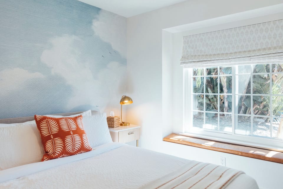 Drift into dreamland in the serene queen bedroom, where a stunning blue sky mural invites tranquility and peace.