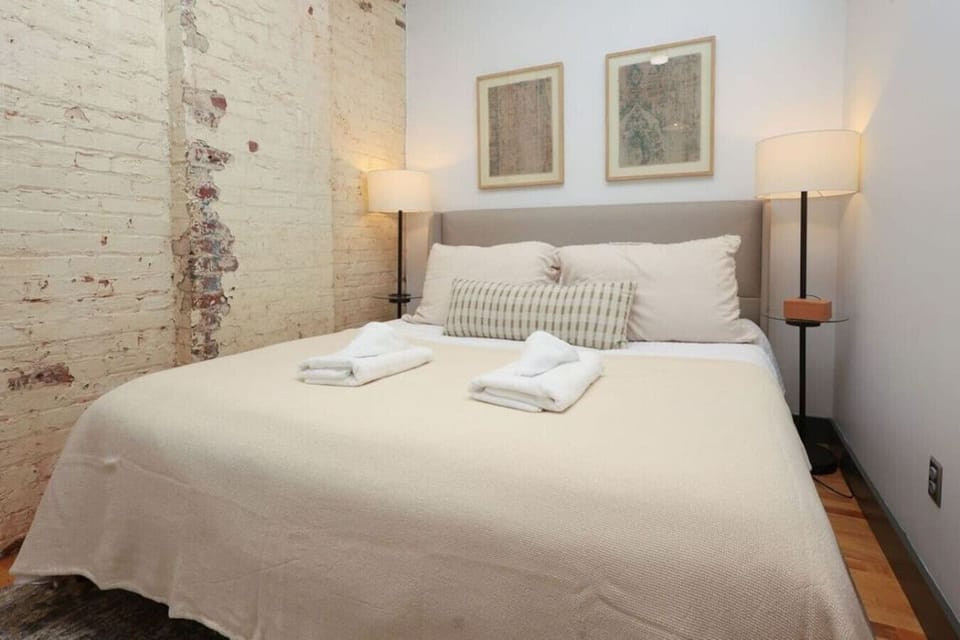 Dreamy Bedroom: Relax on a plush bed surrounded by charming exposed brick and soft lighting!