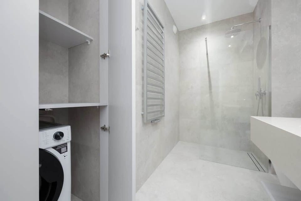 Compact laundry area in bathroom with built-in washing machine, storage shelves, and sleek design.