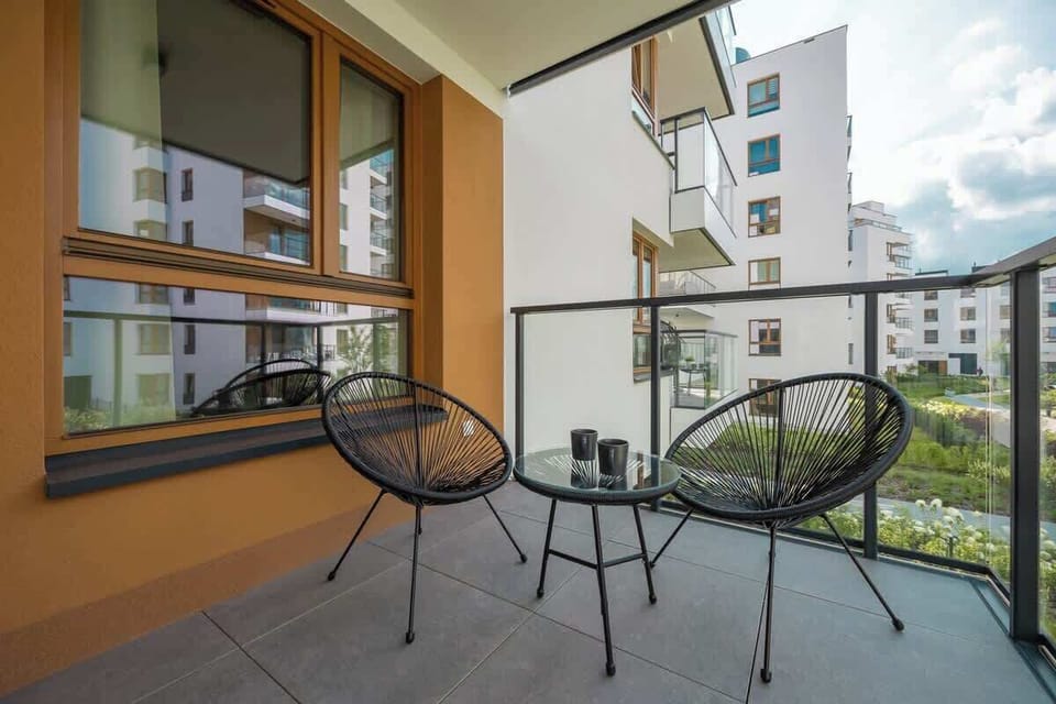 Relaxing balcony with small round table, black chairs, and view of courtyard.