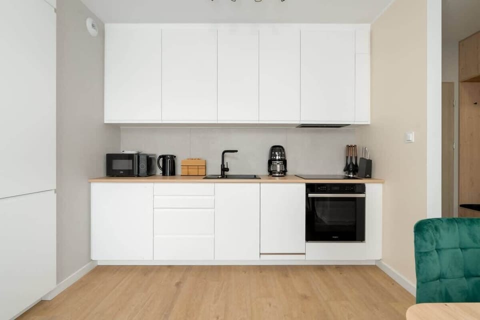 A modern white kitchen with minimalist cabinetry and built-in appliances.