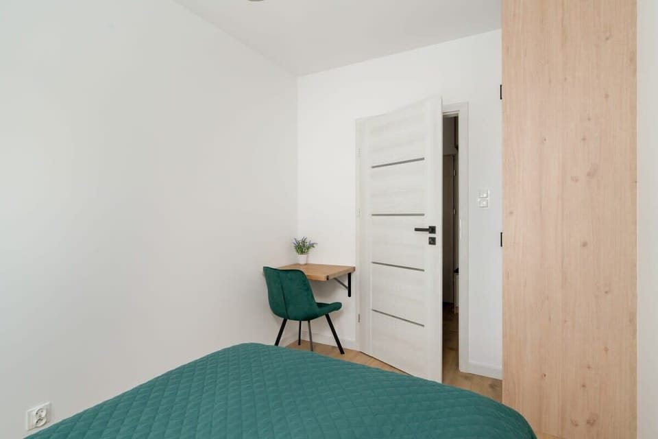A bright bedroom with a double bed, minimalistic decor, and framed pictures on the wall.