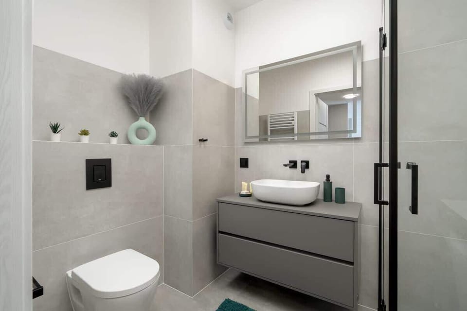 A sleek gray-tiled bathroom with a walk-in shower and washing machine.