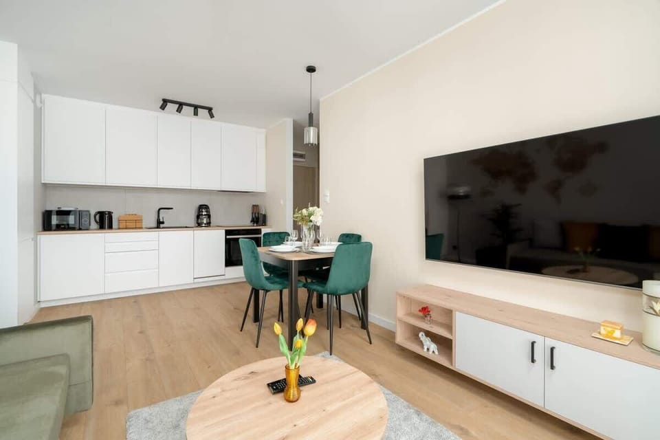 A modern white kitchen with minimalist cabinetry and built-in appliances.