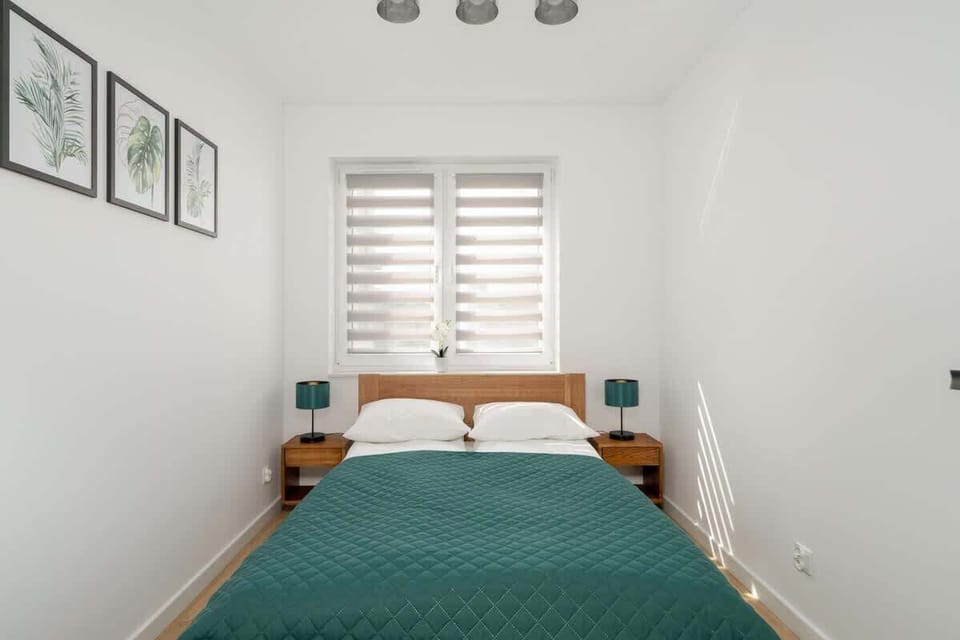 A bright bedroom with a double bed, minimalistic decor, and framed pictures on the wall.