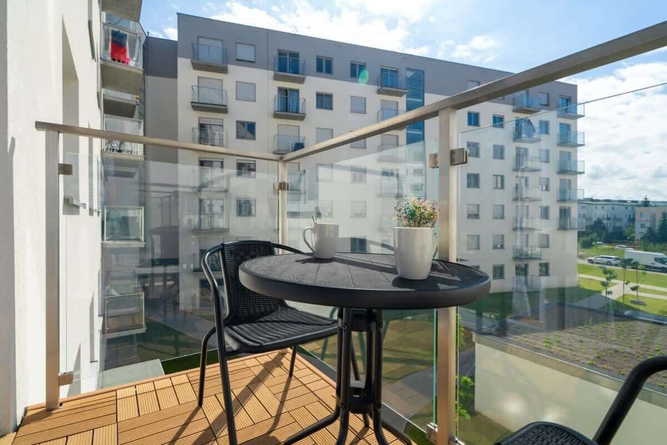 A balcony view with outdoor seating and a cityscape in the background.