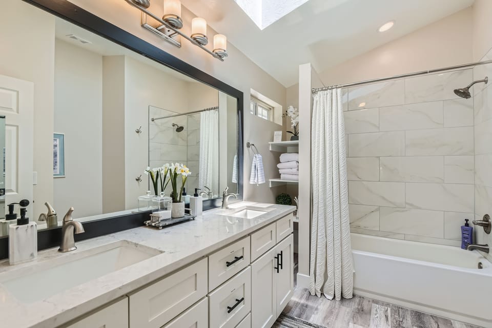 Freshen up in this bright, modern ensuite bathroom featuring a double vanity, large mirror, and a convenient shower/tub combo