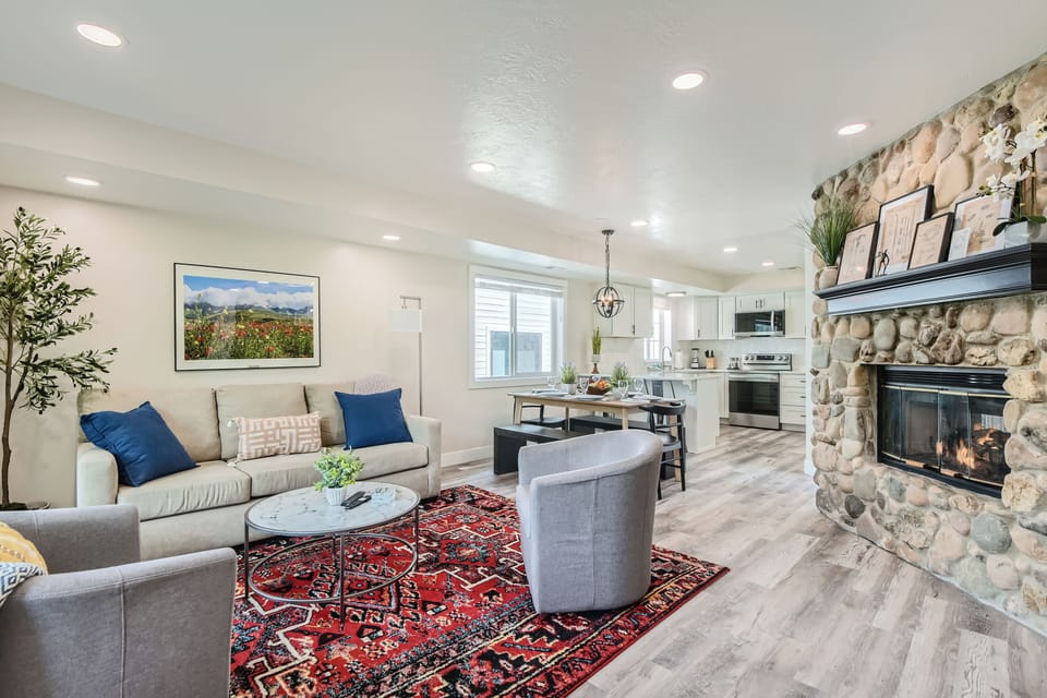 Unwind in the open-concept living area featuring a stunning stone fireplace, comfortable seating, and a seamless flow into the modern kitchen.