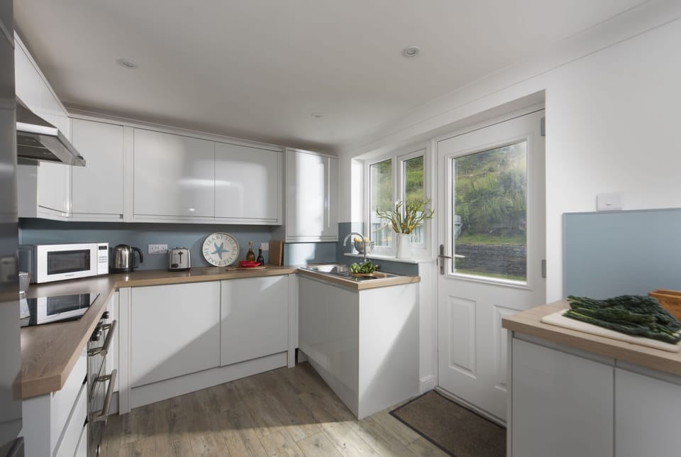 Castaways, Porthtowan. Ground Floor: The kitchen is well equipped with an electric oven and hob, microwave, fridge/freezer, dishwasher and washer/dryer