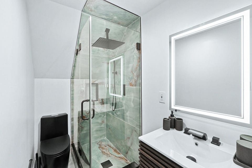 Luxurious bathroom with a spa-inspired rainfall shower, illuminated mirror, and chic contemporary finishes.