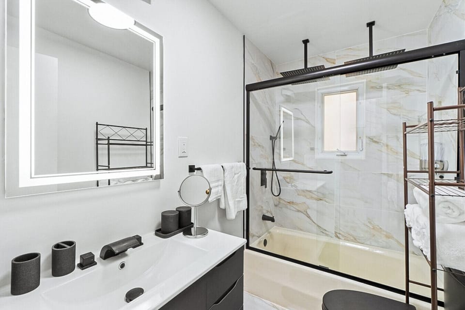 Stylish and contemporary bathroom featuring a spacious glass shower, illuminated mirror, and premium amenities.