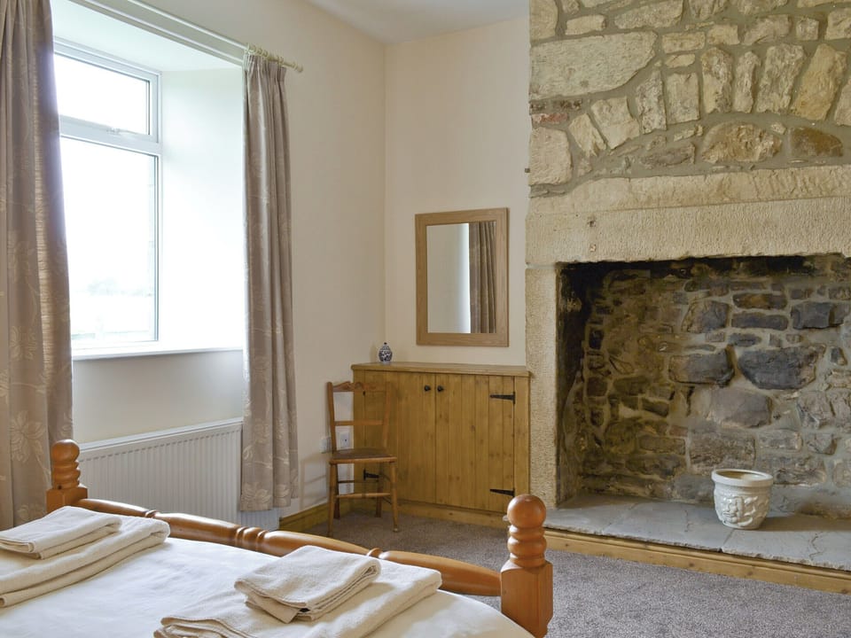 Exposed stone feature fireplace in master bedroom | Curlew Cottage, Belford, near Bamburgh