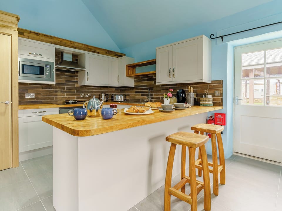 Fully appointed fitted kitchen with breakfast bar | The Cowshed - Musselwick Farm, St Brides
