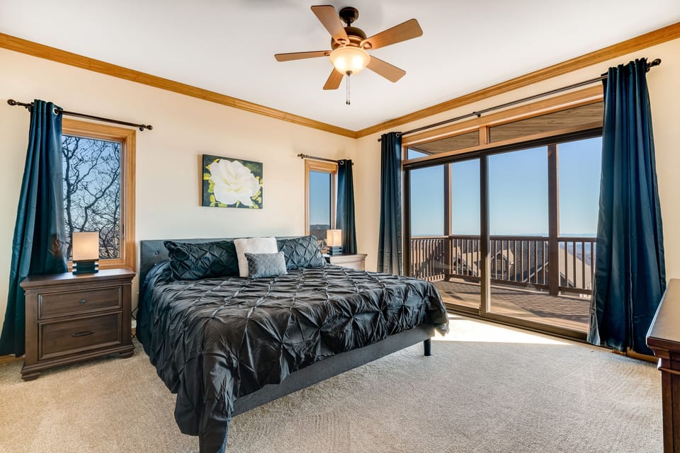 Bedroom 1 features a king bed, ceiling fan, a flat-screen TV, balcony access
