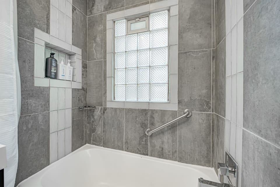 A shower grab bar and supplied shampoo, conditioner, and shower gel.