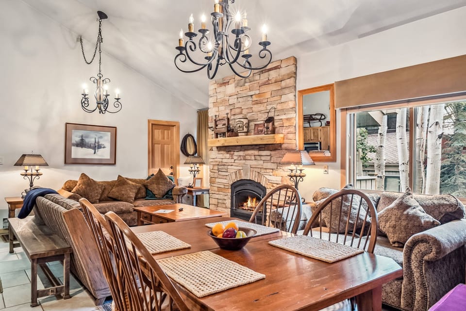 Main Living Space: Open layout, kitchen, living room and dining room, floor-to-ceiling stone mantle, ample natural light