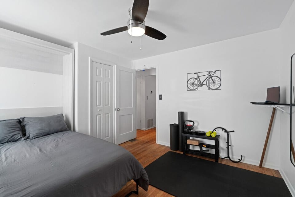 Work & Workout Bedroom – A multi-functional space with a cozy bed, workout area, and desk setup.
