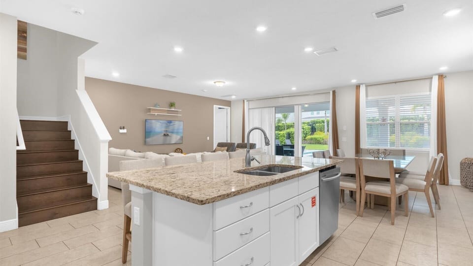 Spacious open-plan kitchen and dining area with elegant granite countertops and abundant natural light, perfect for family gatherings.