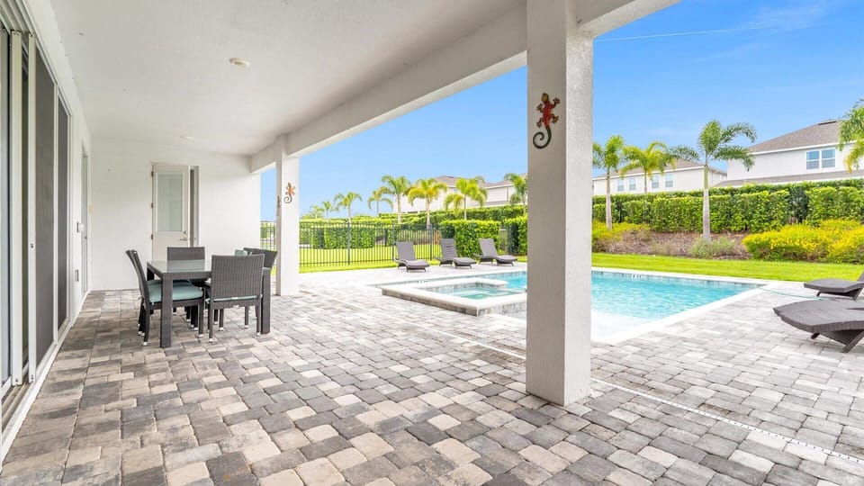 Relax in style on the spacious patio, complete with a dining area and poolside lounge chairs, surrounded by lush landscaping.