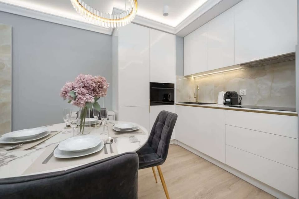 A stylish dining area with a round table and comfortable chairs next to a modern kitchen.